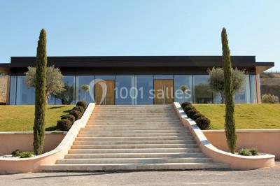 Allée rouge menant à une cérémonie en plein air, entourée de chaises blanches et de jardins verdoyants.
