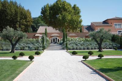 Allée rouge menant à une cérémonie en plein air, entourée de chaises blanches et de jardins verdoyants.