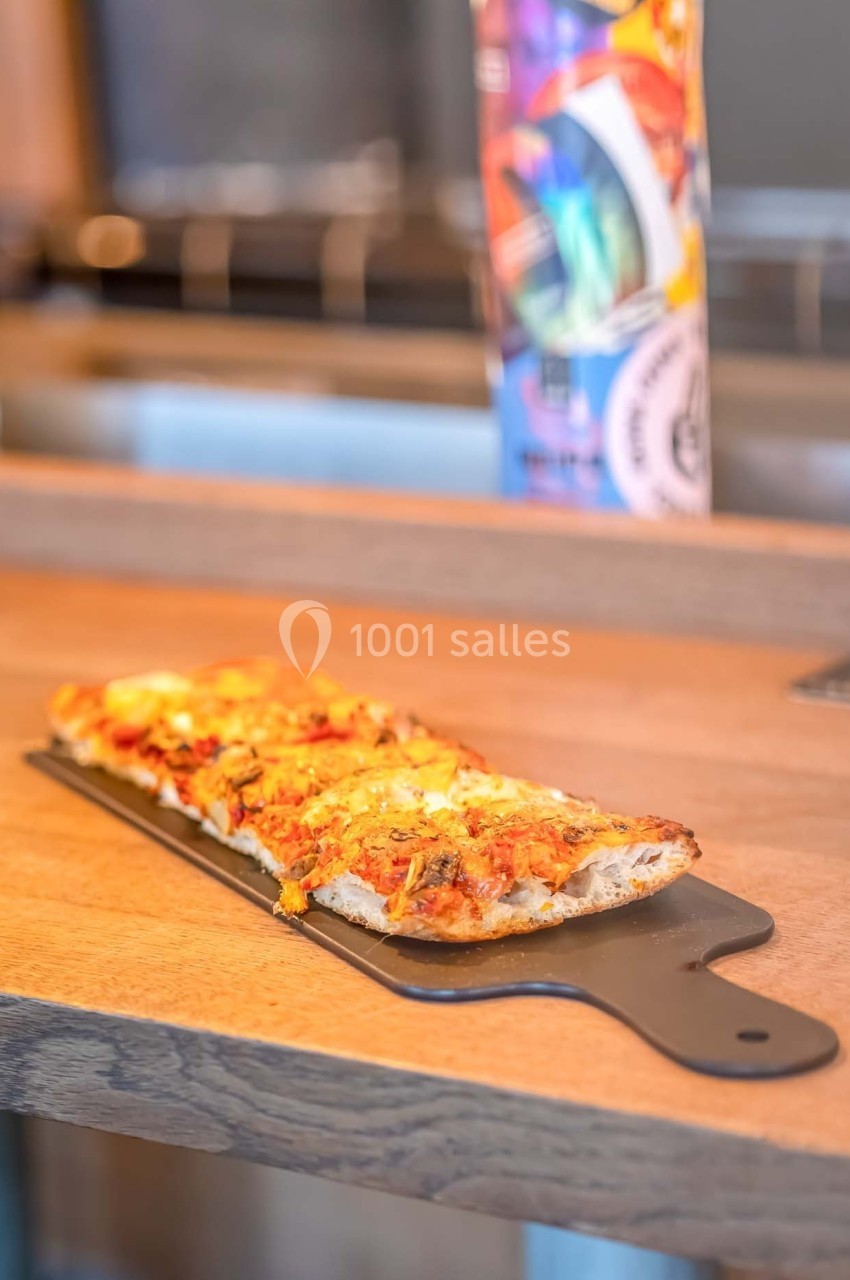 Part de pizza rectangulaire garnie de fromage et de sauce tomate, servie sur une planche en bois.