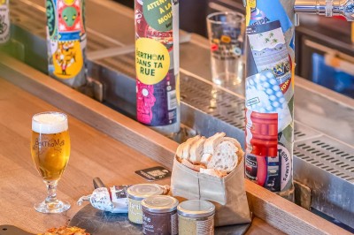 Miniature Location salle Nantes (Loire-Atlantique) - Les Berthom Nantes #19 Logo ’Les Berthom’ noir sur un tissu rouge avec un motif de main formant un signe de paix dans la lettre ’M’.