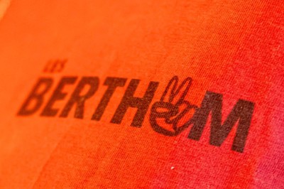 Miniature Location salle Nantes (Loire-Atlantique) - Les Berthom Nantes #23 Logo ’Les Berthom’ noir sur un tissu rouge avec un motif de main formant un signe de paix dans la lettre ’M’.