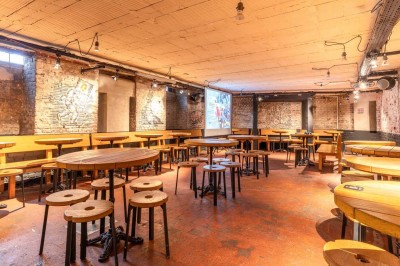 Un couteau et un saucisson sec posé sur une planche en bois, avec un verre de bière en arrière-plan.