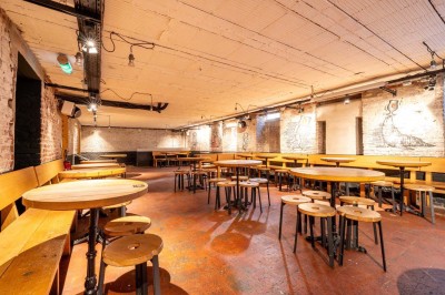 Un couteau et un saucisson sec posé sur une planche en bois, avec un verre de bière en arrière-plan.