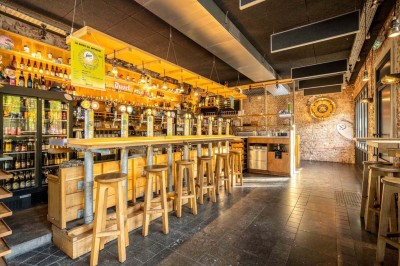 Un couteau et un saucisson sec posé sur une planche en bois, avec un verre de bière en arrière-plan.