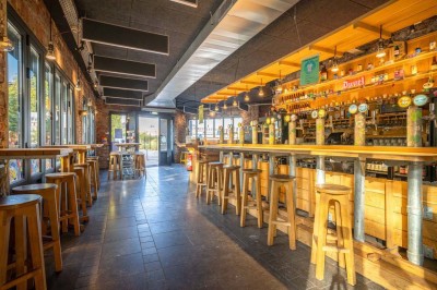 Un couteau et un saucisson sec posé sur une planche en bois, avec un verre de bière en arrière-plan.