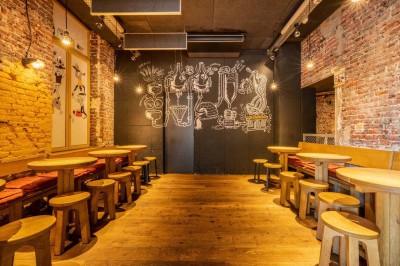 Un couteau et un saucisson sec posé sur une planche en bois, avec un verre de bière en arrière-plan.