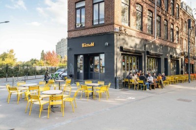 Un couteau et un saucisson sec posé sur une planche en bois, avec un verre de bière en arrière-plan.