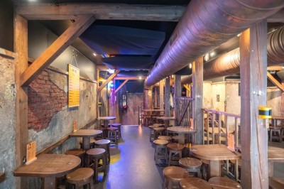 Terrasse d'un café avec des chaises jaunes, des clients attablés et une façade décorée de feuillage automnal.