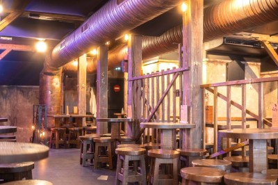 Terrasse d'un café avec des chaises jaunes, des clients attablés et une façade décorée de feuillage automnal.