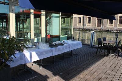 Terrasse bondée d'un restaurant au bord d'un canal, avec des convives profitant de la soirée.