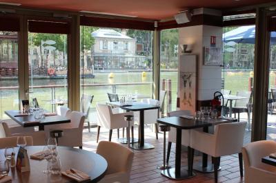 Terrasse bondée d'un restaurant au bord d'un canal, avec des convives profitant de la soirée.
