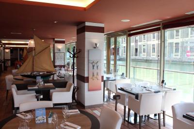 Terrasse bondée d'un restaurant au bord d'un canal, avec des convives profitant de la soirée.