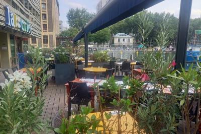Des personnes dînent en terrasse au bord d'un canal, près d'un restaurant éclairé en soirée.