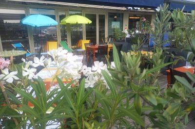 Des personnes dînent en terrasse au bord d'un canal, près d'un restaurant éclairé en soirée.