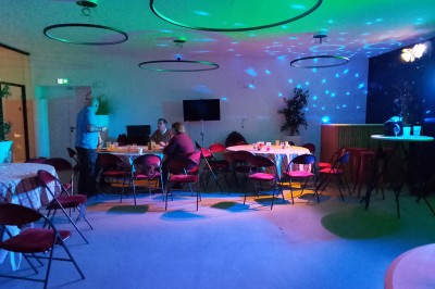 Un Père Noël décoratif près d'un sapin orné de boules argentées et de guirlandes rouges, dans un décor festif.