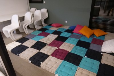 Un Père Noël décoratif près d'un sapin orné de boules argentées et de guirlandes rouges, dans un décor festif.