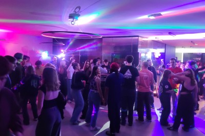 Un Père Noël décoratif près d'un sapin orné de boules argentées et de guirlandes rouges, dans un décor festif.