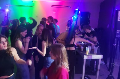 Un Père Noël décoratif près d'un sapin orné de boules argentées et de guirlandes rouges, dans un décor festif.