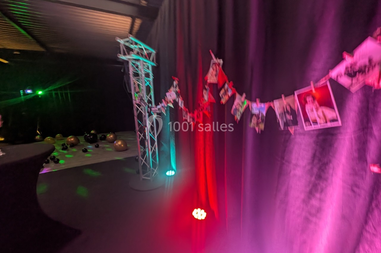 Guirlande de photos suspendue devant un rideau noir, éclairée par des lumières colorées dans une ambiance festive.