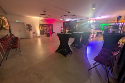 Un Père Noël décoratif près d'un sapin orné de boules argentées et de guirlandes rouges, dans un décor festif.