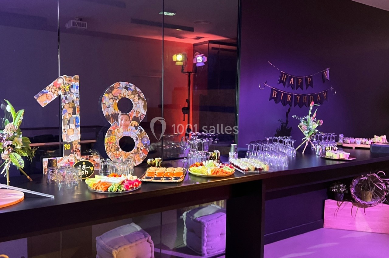 Buffet décoré pour un 18e anniversaire avec des plats variés, des fleurs et une bannière ’Happy Birthday’.