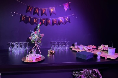 Un Père Noël décoratif près d'un sapin orné de boules argentées et de guirlandes rouges, dans un décor festif.