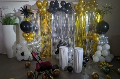 Un Père Noël décoratif près d'un sapin orné de boules argentées et de guirlandes rouges, dans un décor festif.