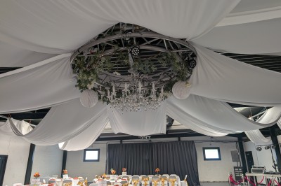 Un Père Noël décoratif près d'un sapin orné de boules argentées et de guirlandes rouges, dans un décor festif.