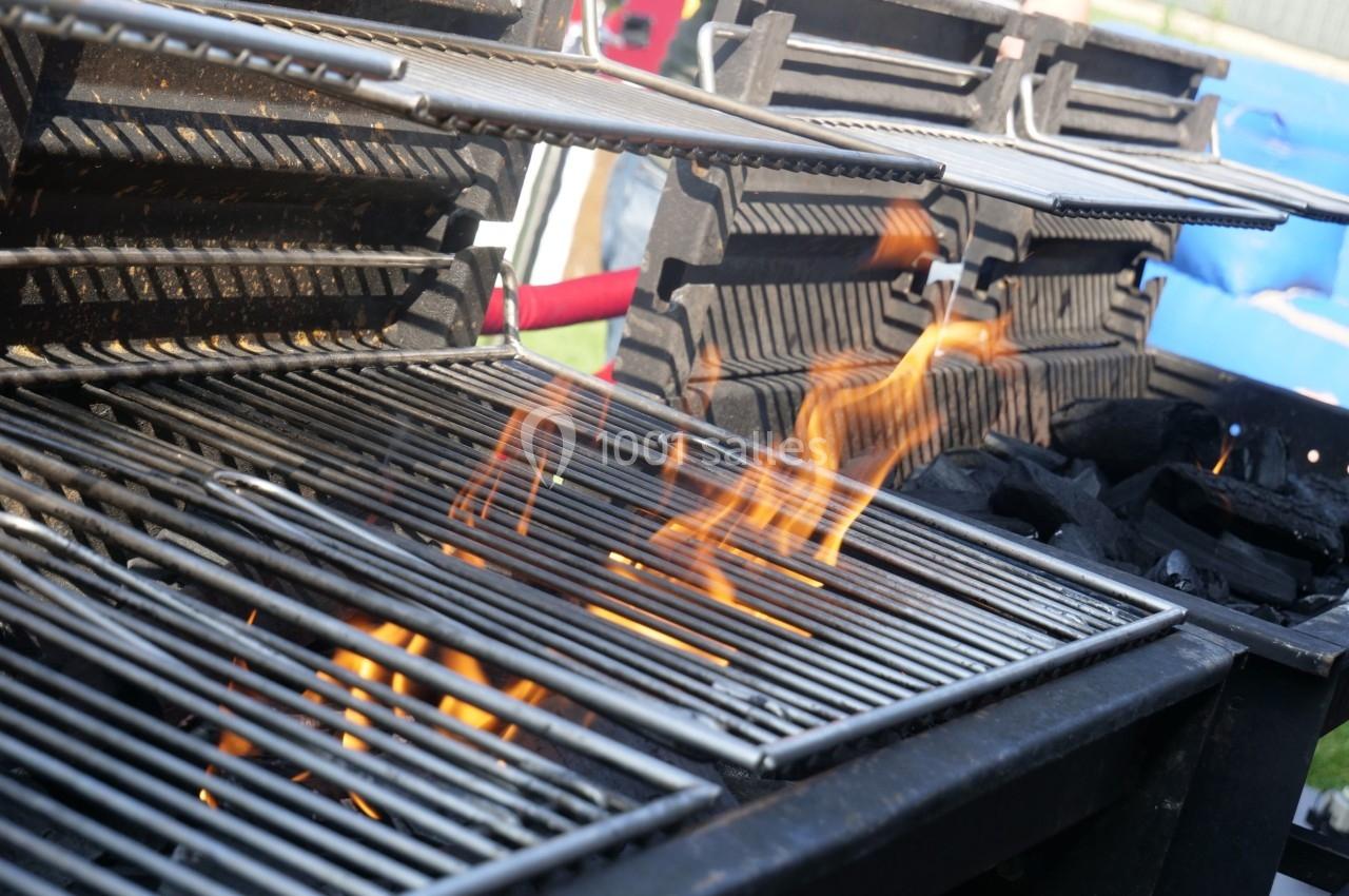Flammes s'élevant sur un barbecue à charbon avec des grilles métalliques en extérieur.
