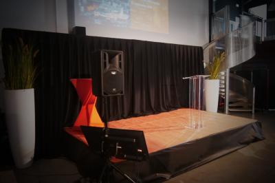 Un grand groupe de jeunes assis dehors sur un sol en béton, près de bâtiments sous un ciel nuageux.