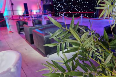 Un grand groupe de jeunes assis dehors sur un sol en béton, près de bâtiments sous un ciel nuageux.