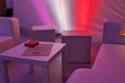 Un grand groupe de jeunes assis dehors sur un sol en béton, près de bâtiments sous un ciel nuageux.