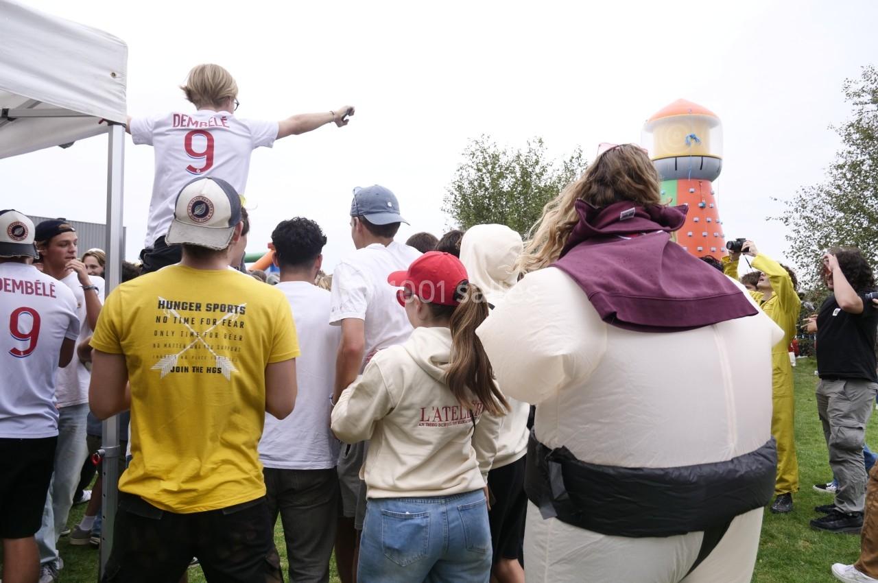 Un groupe de personnes rassemblées en plein air près d'une structure gonflable colorée.
