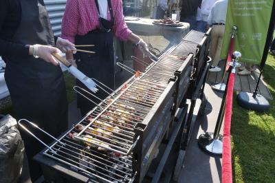 Un grand groupe de jeunes assis dehors sur un sol en béton, près de bâtiments sous un ciel nuageux.