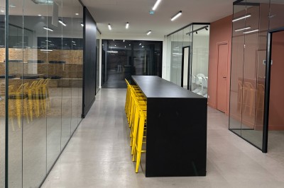 Un grand groupe de jeunes assis dehors sur un sol en béton, près de bâtiments sous un ciel nuageux.