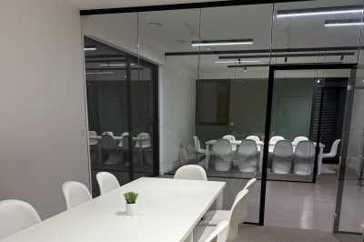 Un grand groupe de jeunes assis dehors sur un sol en béton, près de bâtiments sous un ciel nuageux.