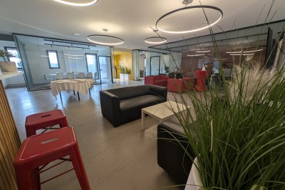 Un grand groupe de jeunes assis dehors sur un sol en béton, près de bâtiments sous un ciel nuageux.