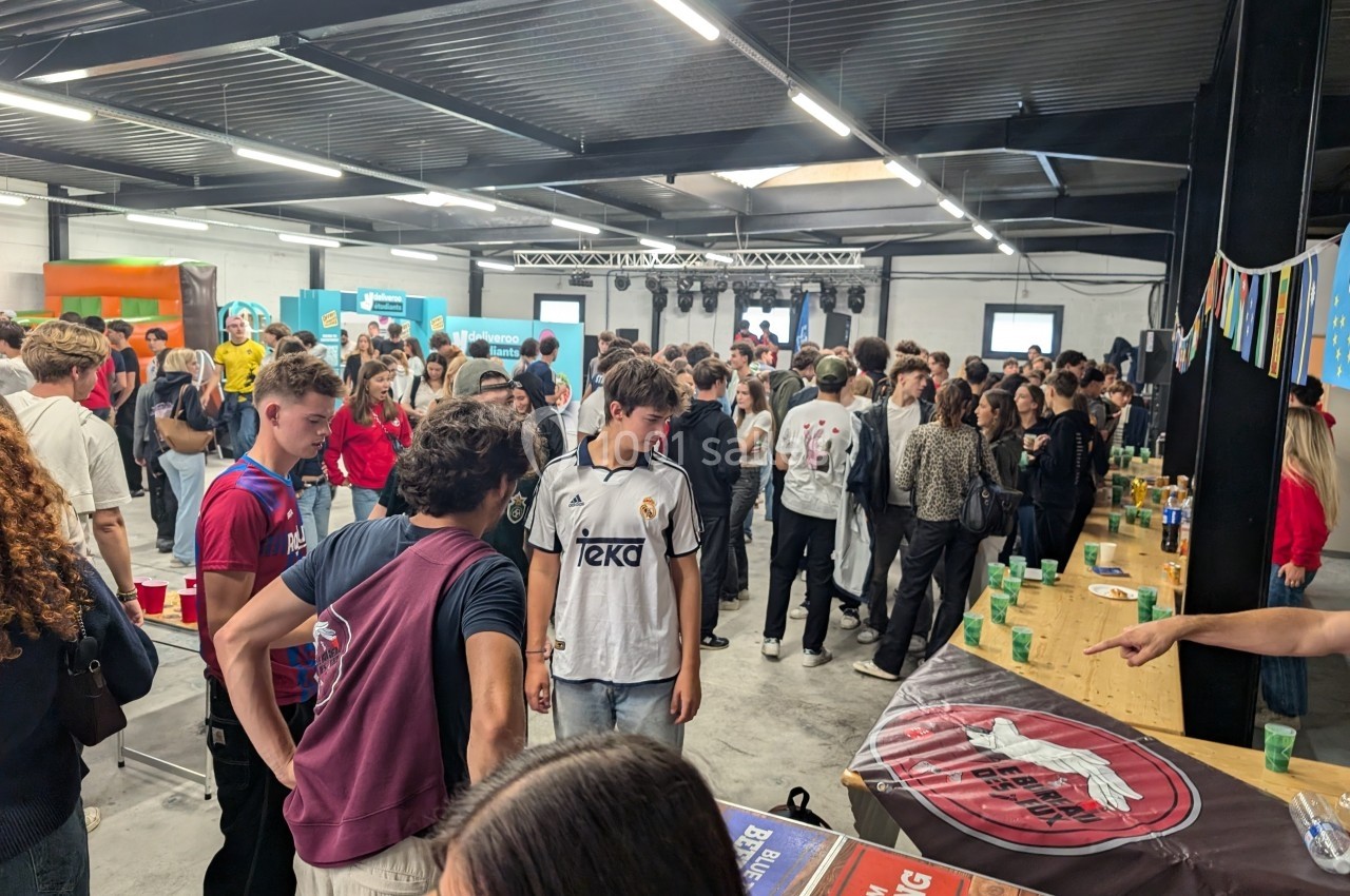 Groupe de jeunes rassemblés dans une salle animée, discutant près de tables avec des gobelets et décorations.