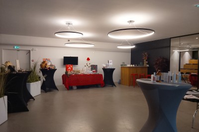Un grand groupe de jeunes assis dehors sur un sol en béton, près de bâtiments sous un ciel nuageux.