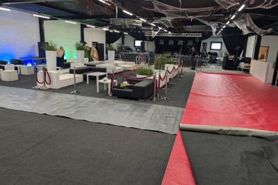 Un grand groupe de jeunes assis dehors sur un sol en béton, près de bâtiments sous un ciel nuageux.