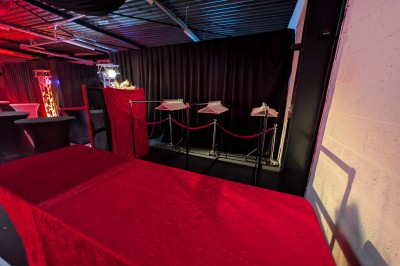 Des enfants colorient des dessins autour d'une table ronde, entourés d'adultes dans un espace intérieur animé.