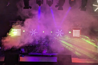 Des enfants colorient des dessins autour d'une table ronde, entourés d'adultes dans un espace intérieur animé.