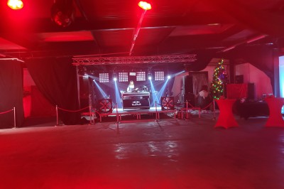 Des enfants colorient des dessins autour d'une table ronde, entourés d'adultes dans un espace intérieur animé.