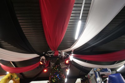 Des enfants colorient des dessins autour d'une table ronde, entourés d'adultes dans un espace intérieur animé.