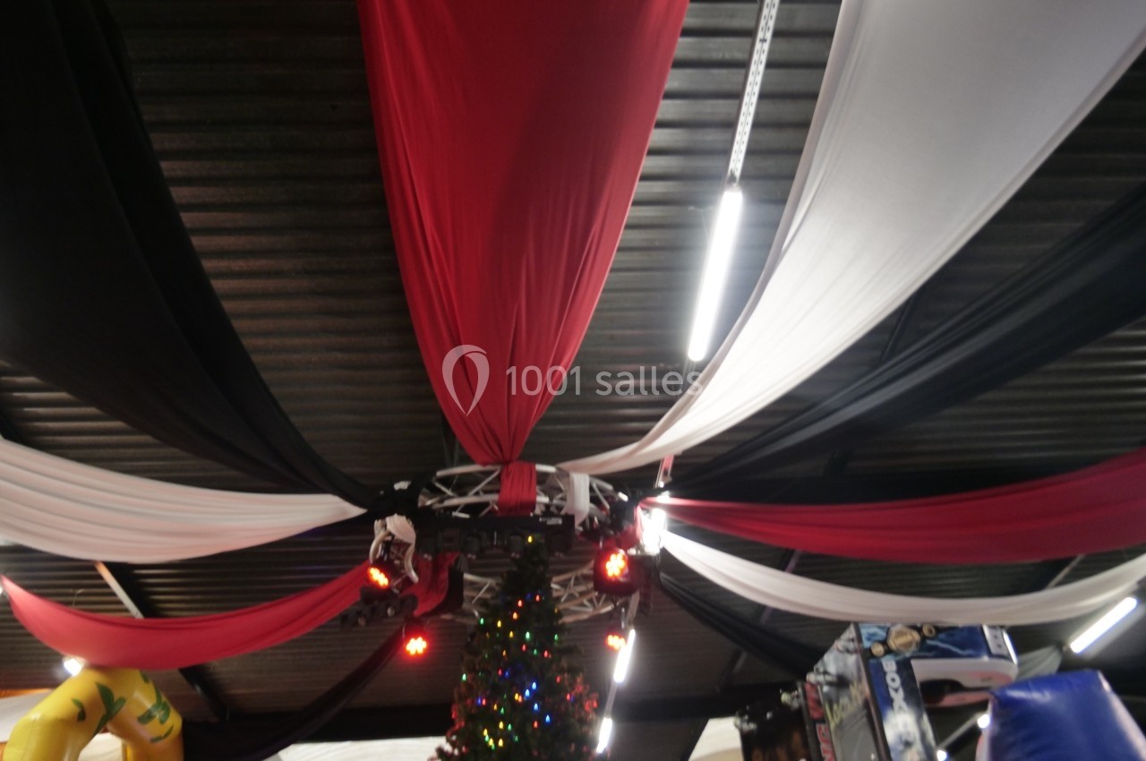 Tissu rouge, noir et blanc suspendu au plafond d'un espace intérieur, avec un sapin décoré en dessous.