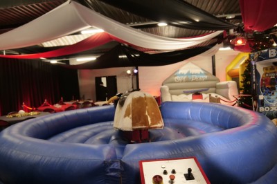 Des enfants colorient des dessins autour d'une table ronde, entourés d'adultes dans un espace intérieur animé.