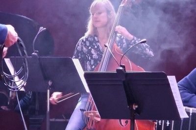 Des enfants colorient des dessins autour d'une table ronde, entourés d'adultes dans un espace intérieur animé.