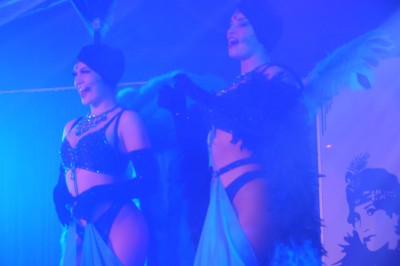 Des enfants colorient des dessins autour d'une table ronde, entourés d'adultes dans un espace intérieur animé.