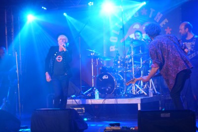 Des enfants colorient des dessins autour d'une table ronde, entourés d'adultes dans un espace intérieur animé.