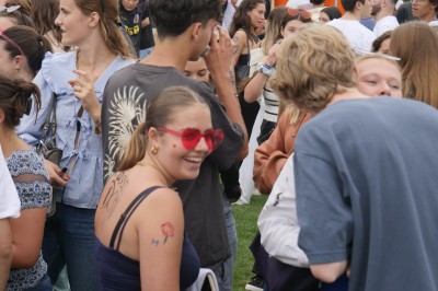 Des enfants colorient des dessins autour d'une table ronde, entourés d'adultes dans un espace intérieur animé.